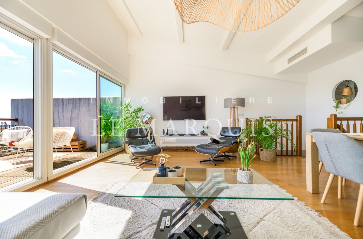 Bel espace de vie avec poutres apparentes aux généreux volumes, baigné de lumière et ouvert sur l'une des terrasses