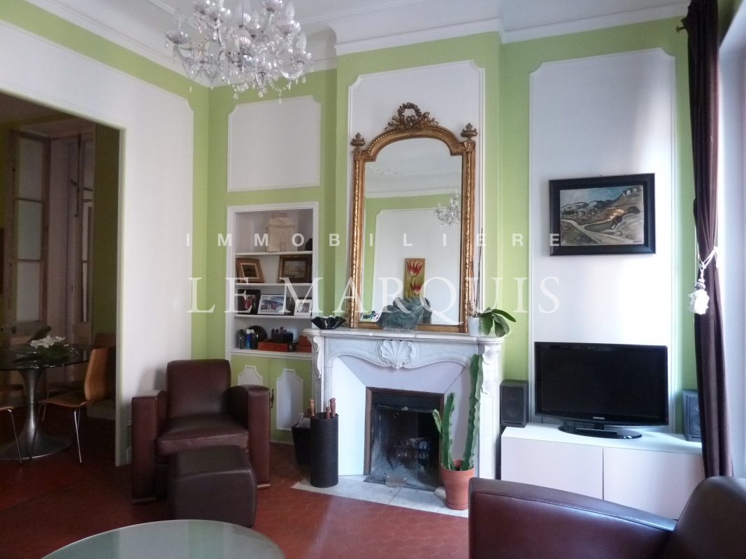 Salon avec cheminée, tomettes et moulures ouvert sur salle à manger